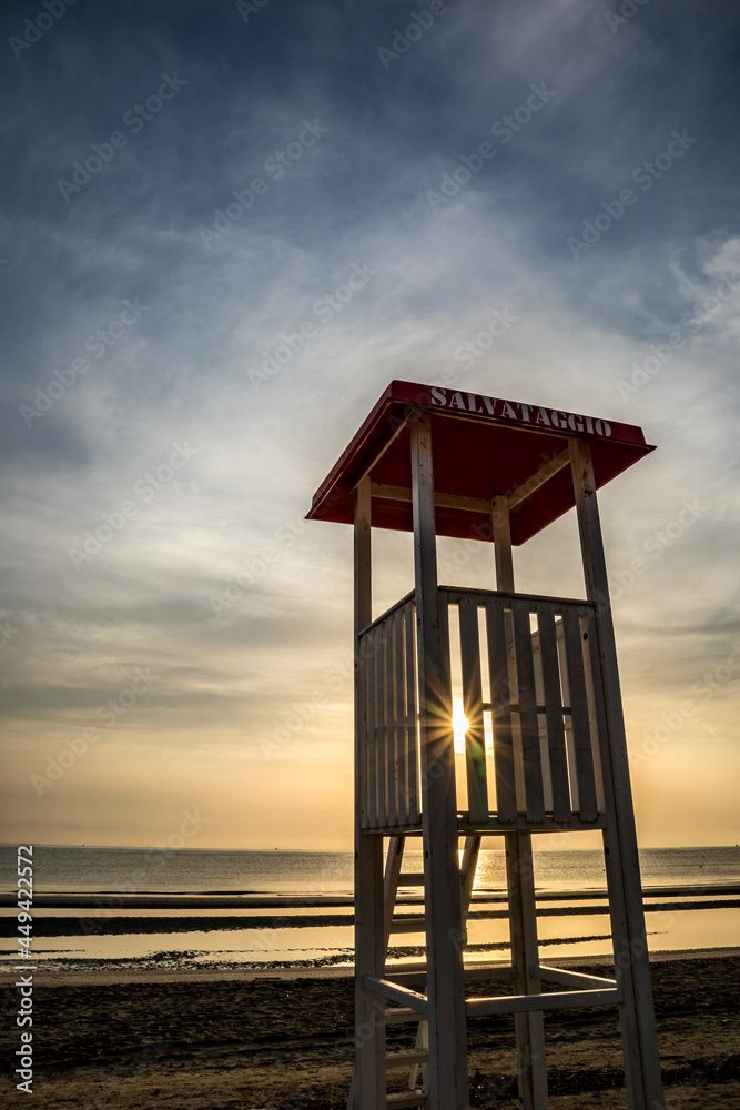 Sun rays shine with beautiful diffraction effect from the lifeguard cabin at the shores of Adriatic Sea near the Senigallia resort town, Eastern Italy