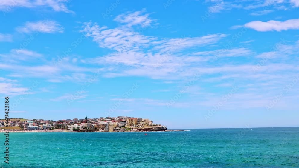 Panning shot from top to bottom of the clear sky, the clear ocean, and the buildings on the shore Panning shot from top to bottom of the clear sky, the clear ocean, and the buildings on the shore