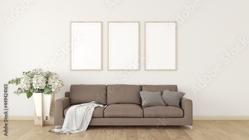 3 white photo frames on the cream wall The interior is decorated with brown sofas, pillows, and plant pots on the wooden floor. © DJSPIDA FOTO