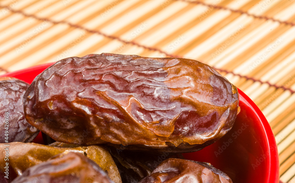Obraz premium Big luxury dried date fruit in bowls on the bamboo mat, kurma ramadan kareem concept, close up.