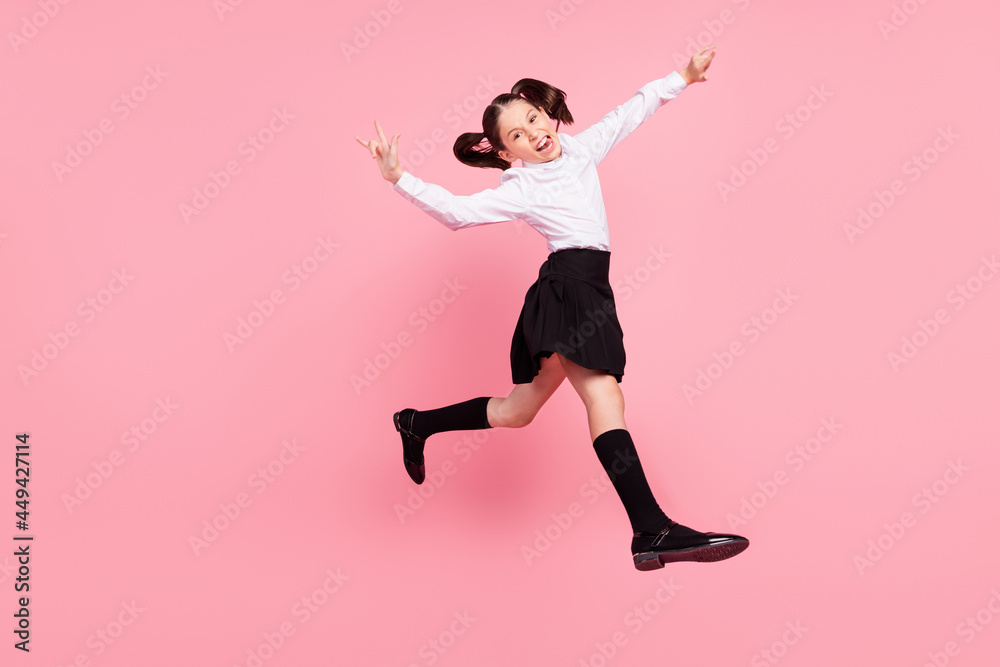 Full length photo of crazy happy positive girl jump up show rock signs walk isolated on pink color background