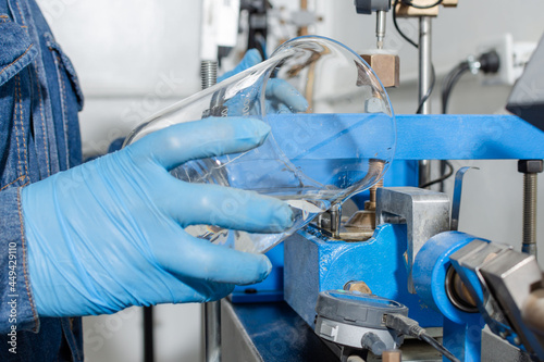 Industrial worker hands with blue latex gloves holding a glass container while pouring water