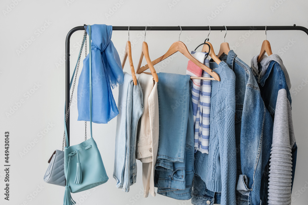 Rack with stylish clothes near light wall