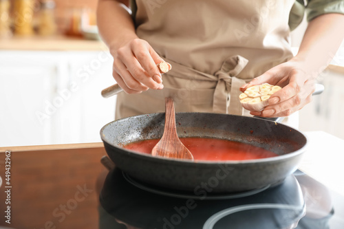 Woman preparing tomato sauce in kitchen