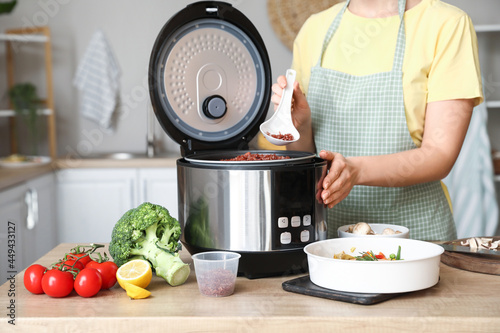 фотографія Woman preparing rice in multi cooker at  kitchen table