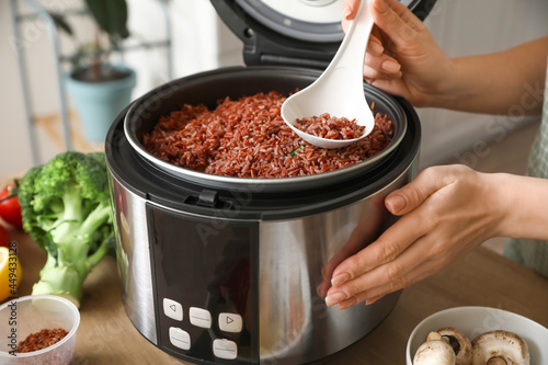 Φωτογραφία Woman preparing rice in multi cooker at  kitchen table