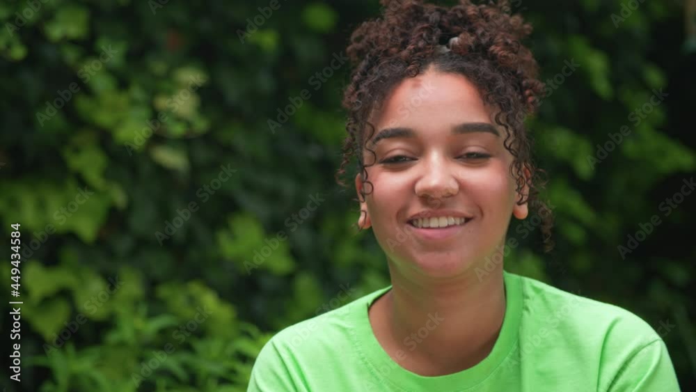 Beautiful mixed race African American girl teenager young woman with perfect teeth happy smiling wearing a green t-shirt outside