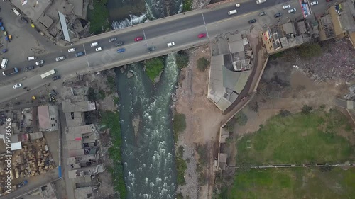 Aerial drone view of the Rimac river and Huachipa waterfall seen from above in bird's eye view next to the zoo and lagoons and highway with cars and birds flying in the cloudy day in 4K photo