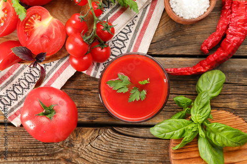 Glass of tasty tomato juice on wooden background