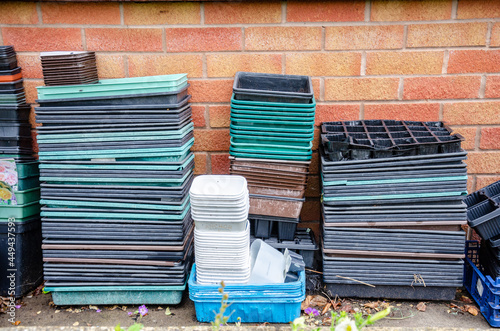 Empty seed trays stacked next to a wall of a house in a residential garden.