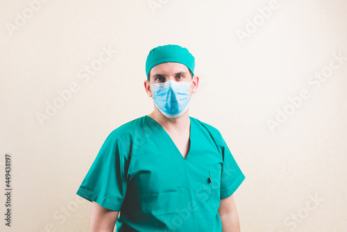 Doctor in green surgeon suitand protective breathing mask looking forward on yellow background photo