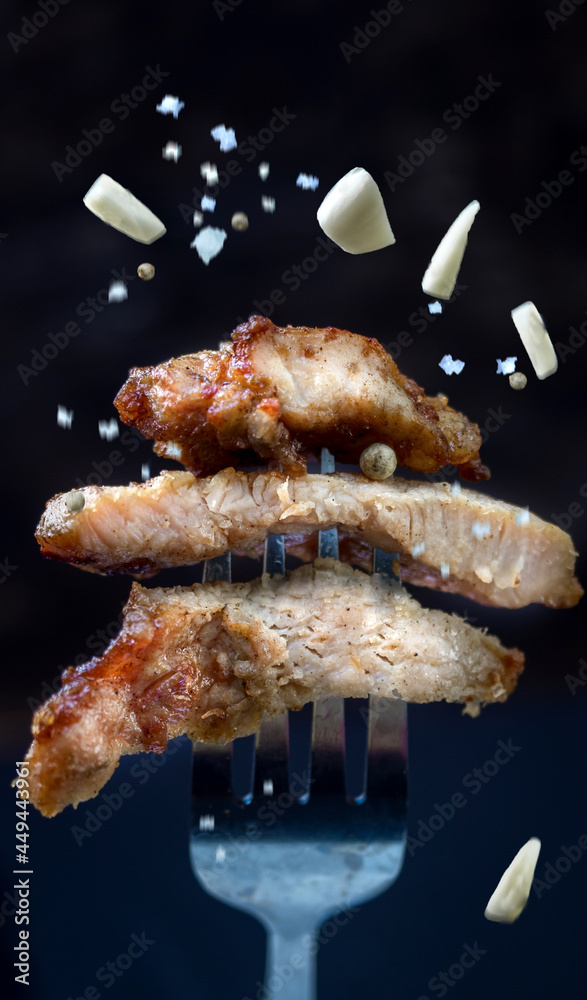 beef steak with spices on a black background. Beef steak on a fork sprinkled with garlic and sea salt beef steak with spices on a black background. Beef steak on a fork sprinkled with garlic and sea salt