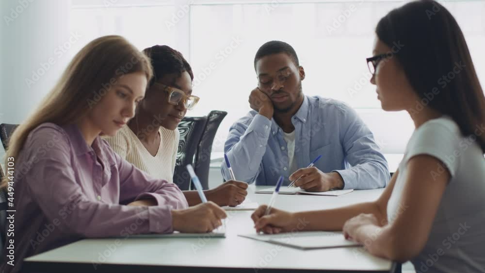 Time of self education. Diverse young students sitting at campus together and doing homework, writing tasks Time of self education. Diverse young students sitting at campus together and doing homework, writing tasks