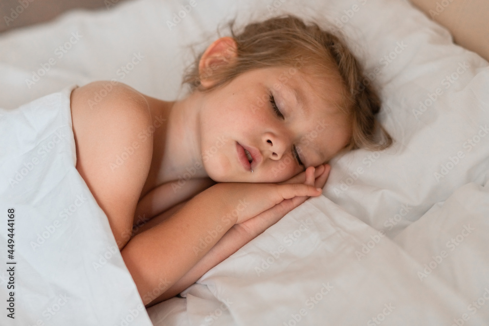 Adorable little girl sleeping in bed with white linens. Place for your text. Healthy baby sleep. Adorable little girl sleeping in bed with white linens. Place for your text. Healthy baby sleep.