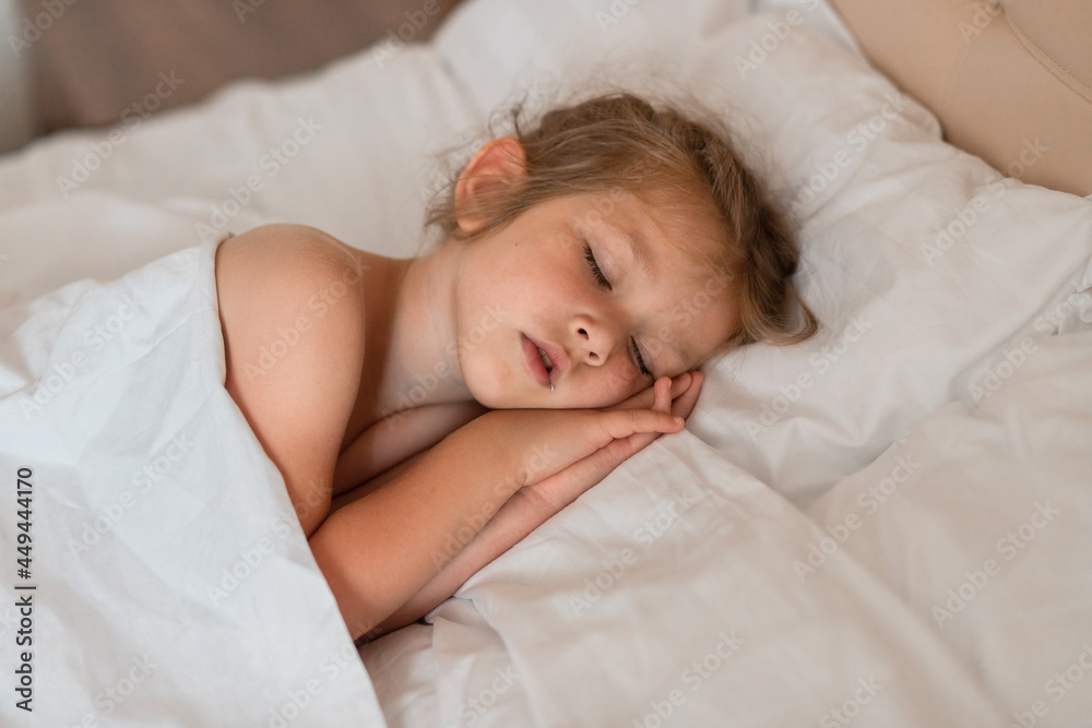 Adorable little girl sleeping in bed with white linens. Place for your text. Healthy baby sleep. Adorable little girl sleeping in bed with white linens. Place for your text. Healthy baby sleep.