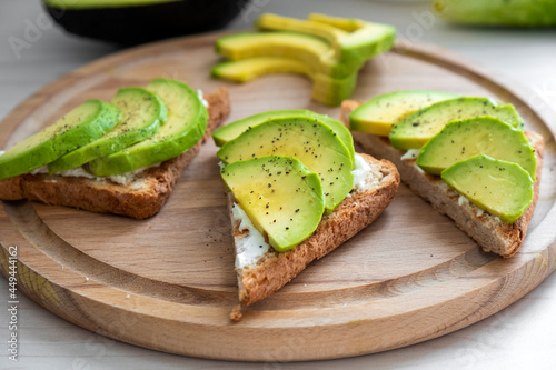 Healthy avocado toast with soft cheese, sliced avocado, salt and pepper on toasted bread for breakfast or lunch. Healthy snack, keto diet or dieting concept. Recipe of vegan food for everyday cooking.
