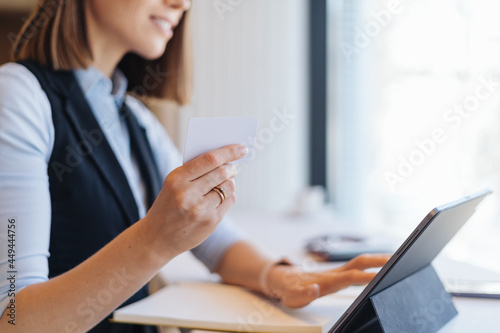 Woman smiling holding credit card shopping online with tablet computer buying and payment, girl using debit card purchase or transaction of finance, lifestyle and e-commerce concept.