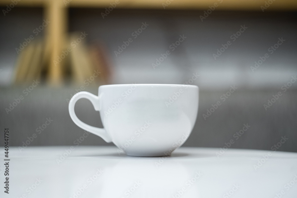 Fototapeta premium White ceramic mug with blurred background and white table