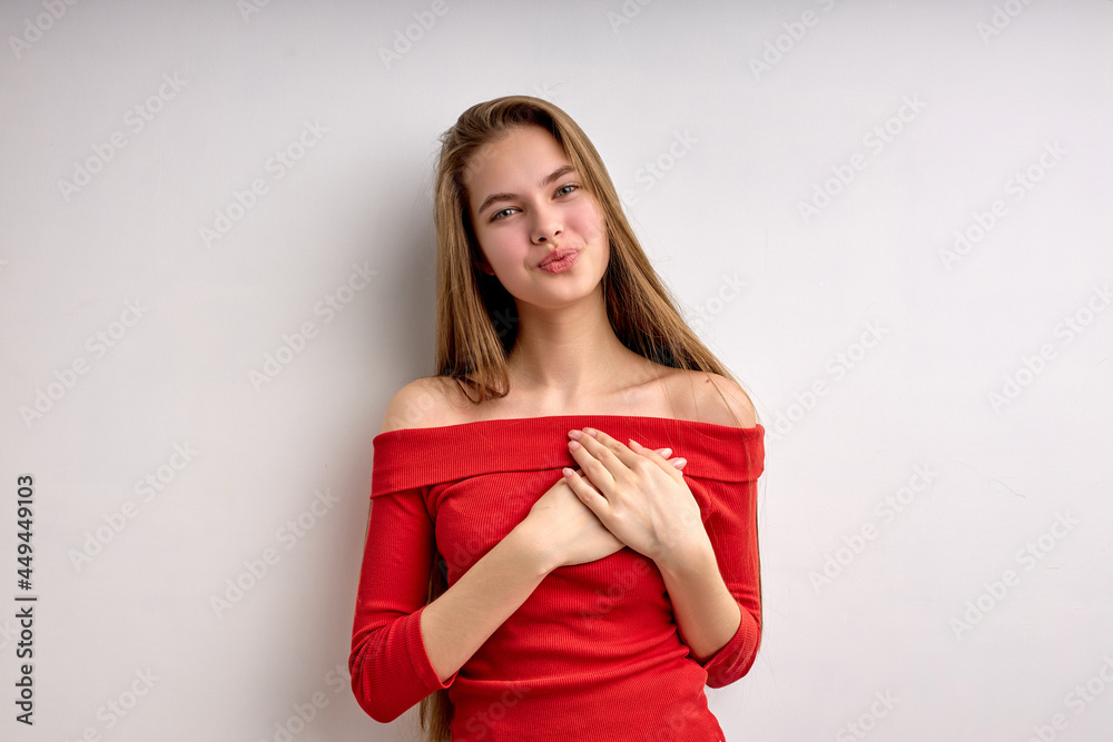 Cute pretty caucasian teen girl expressing gratitude, holding hands on chest, thankful for something, nice lady in casual red shirt look at camera, isolated on white studio background, copy space Cute pretty caucasian teen girl expressing gratitude, holding hands on chest, thankful for something, nice lady in casual red shirt look at camera, isolated on white studio background, copy space