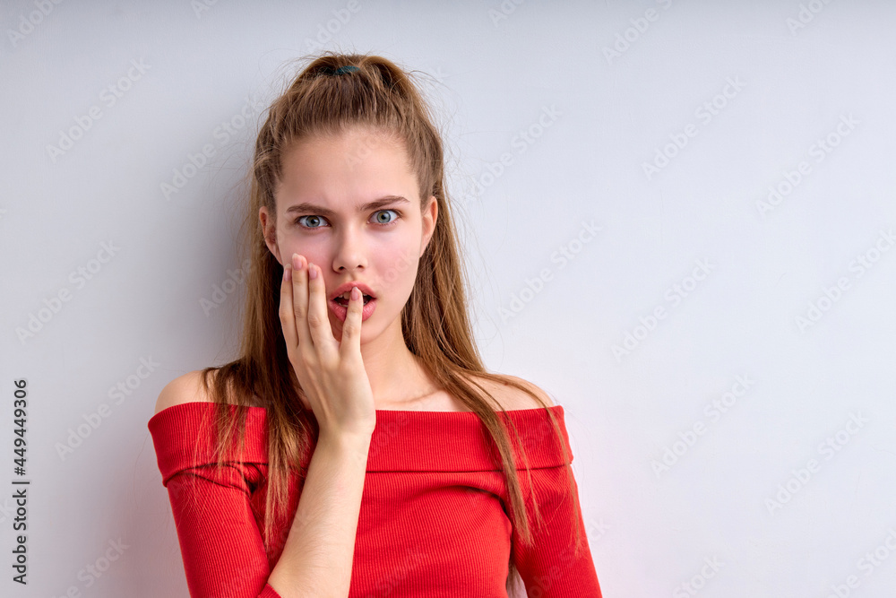shocked Caucasian female opens mouth widely from surprisement, feels troubled and concerned, wearing red shirt isolated on white studio background, copy space. female covering mouth with hands shocked Caucasian female opens mouth widely from surprisement, feels troubled and concerned, wearing red shirt isolated on white studio background, copy space. female covering mouth with hands