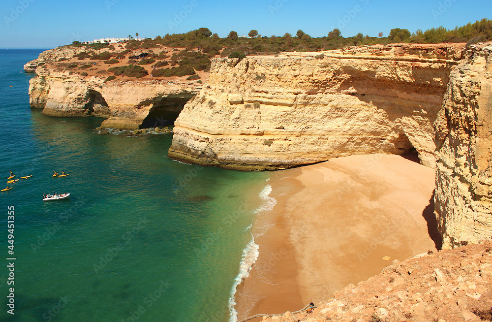 Corredoura Beach, some cliffs, natural arches and tourist boats on the coast of Algarve, southern Portugal