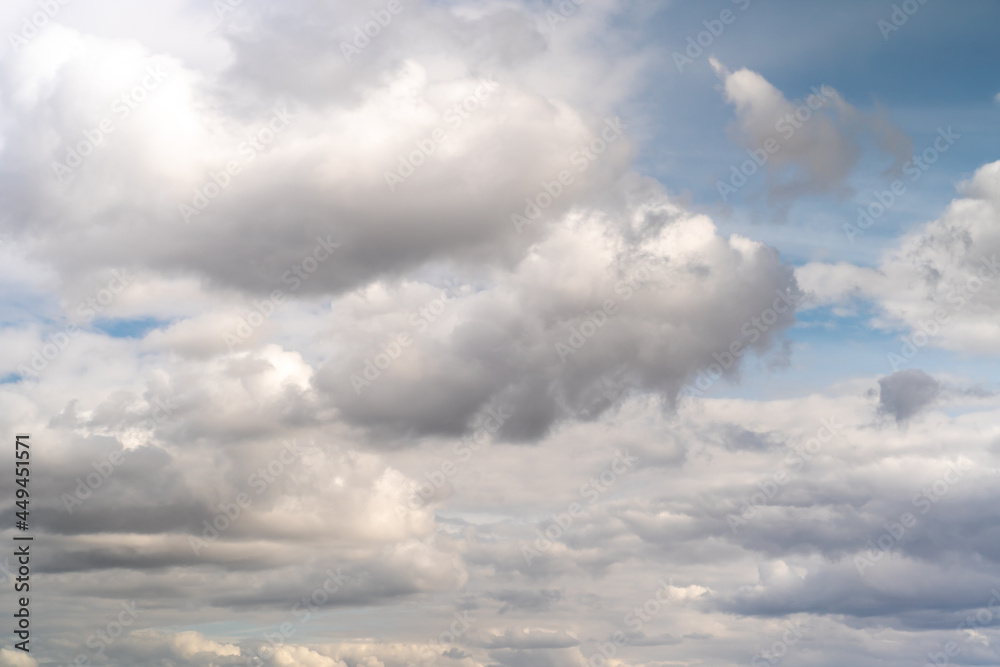 Beautiful fluffy clouds in the evening sky. The sunlight gives a side light on the clouds. Clouds before rain.