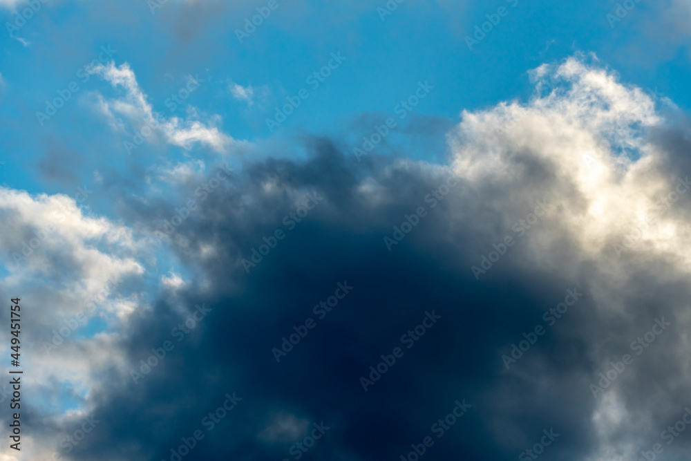 Fototapeta premium Beautiful fluffy clouds in the evening sky. The sunlight gives a side light on the clouds. Clouds before rain.