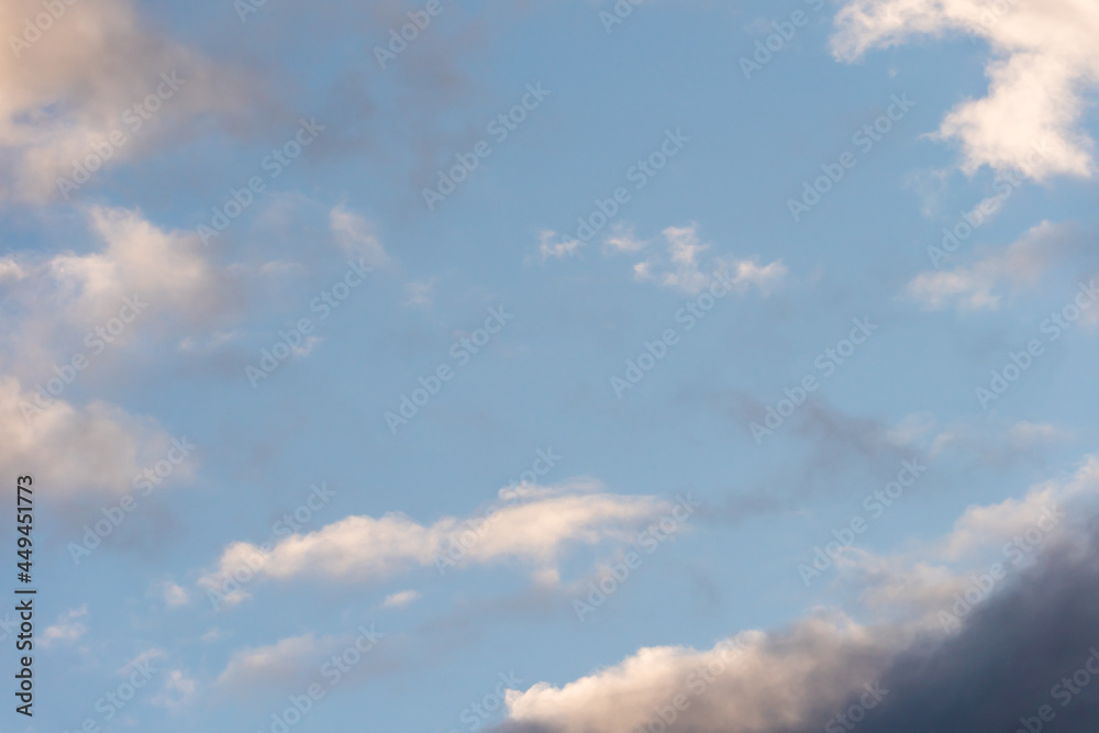 Beautiful fluffy clouds in the evening sky. The sunlight gives a side light on the clouds. Clouds before rain.