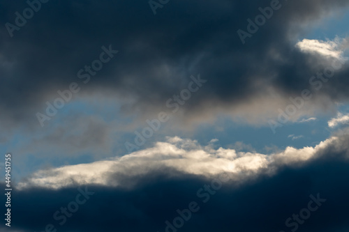 Beautiful fluffy clouds in the evening sky. The sunlight gives a side light on the clouds. Clouds before rain.