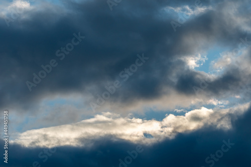 Beautiful fluffy clouds in the evening sky. The sunlight gives a side light on the clouds. Clouds before rain.