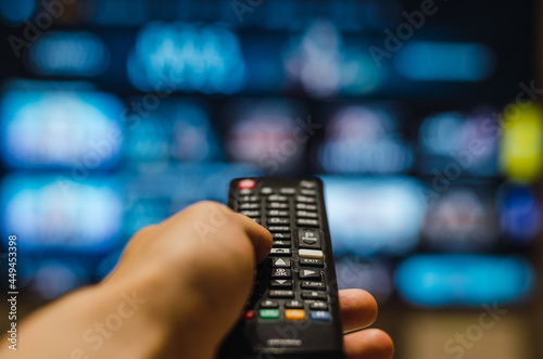 Принти на полотні Cropped hand of man holding remote control and watching smart tv in living room