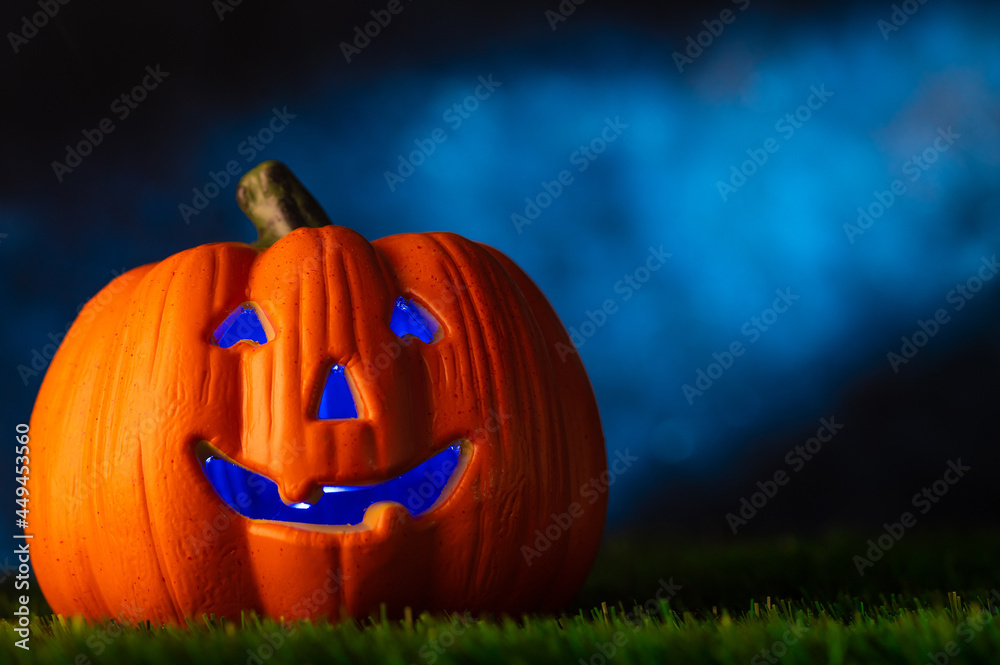 Obraz premium Original composition. Halloween autumn traditional holiday. Mystical fabulous pumpkin on green grass against the backdrop of the night dark sky. Full moon. There is a place for an inscription.