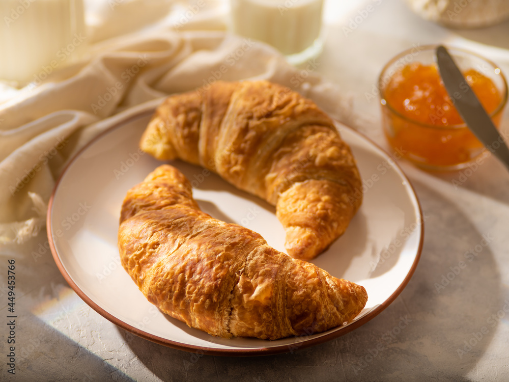 Croissants, jam, milk. Close-up. Focusing on the foreground. Tasty breakfast. White silk tablecloth. Restaurant, hotel and advertising business. Home kitchen. There is no one in the photo. Croissants, jam, milk. Close-up. Focusing on the foreground. Tasty breakfast. White silk tablecloth. Restaurant, hotel and advertising business. Home kitchen. There is no one in the photo.