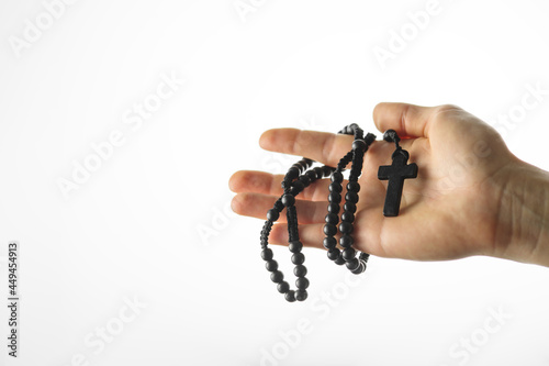 Rosary and crucifix in a woman's hand. Simple white background. Minimalism. Christianity, Catholicism, religion, spirituality, prayer, meditation.