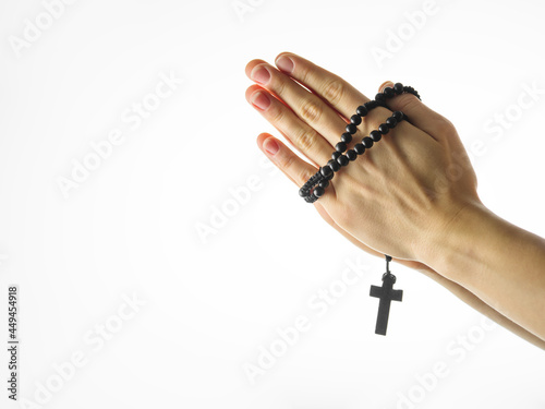 Rosary and crucifix in a female hand on a white background. Minimalism. Religion, Catholicism, spirituality, faith, meditation. There is an empty space for an inscription.