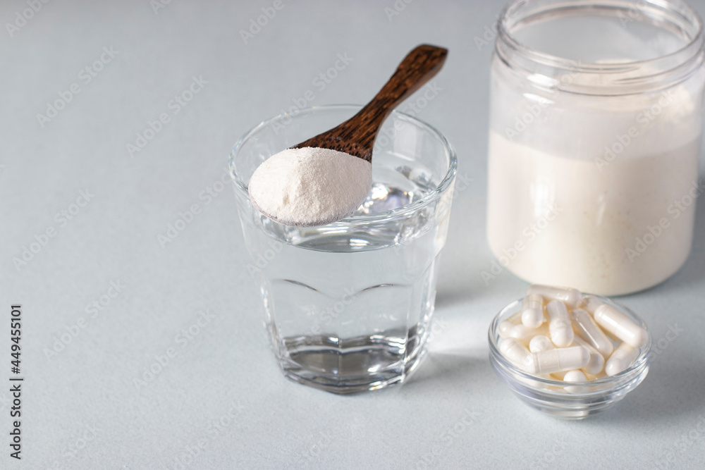 Collagen powder in spoon on glass of water, collagen capsules and jar of powder on light background. Healthy and anti-aging concept. Collagen powder in spoon on glass of water, collagen capsules and jar of powder on light background. Healthy and anti-aging concept.