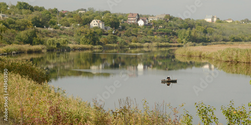 Still waters of meandering Inhul River, Ukraine, with a sloping bank, pastures and houses during Indian summer. Early fall countryside river landscape background