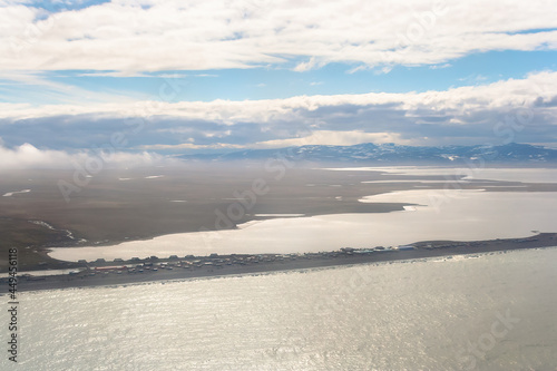 Aerial view of the small Chukchi village of Inchoun, located on a spit on the coast of the Arctic Ocean. Top view of the sea, lagoon, tundra and mountains. Arctic settlement in the Far North of Russia