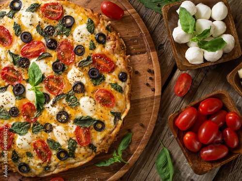 Quadro em tela Pizza on a wooden tray and ingredients - tomatoes and mushrooms, mint leaves