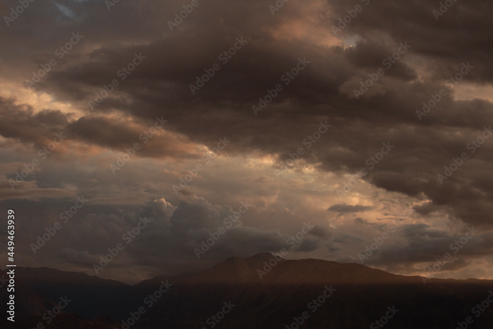 Dramatic sunset in the mountains. View of the Andes mountain range and cloudy sky with beautiful nightfall colors.