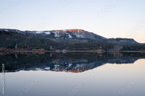 Alpine landscape at nightfall. Magical view of the Andes mountains, forest and lake at sunset. Beautiful symmetrical reflection in the water. 