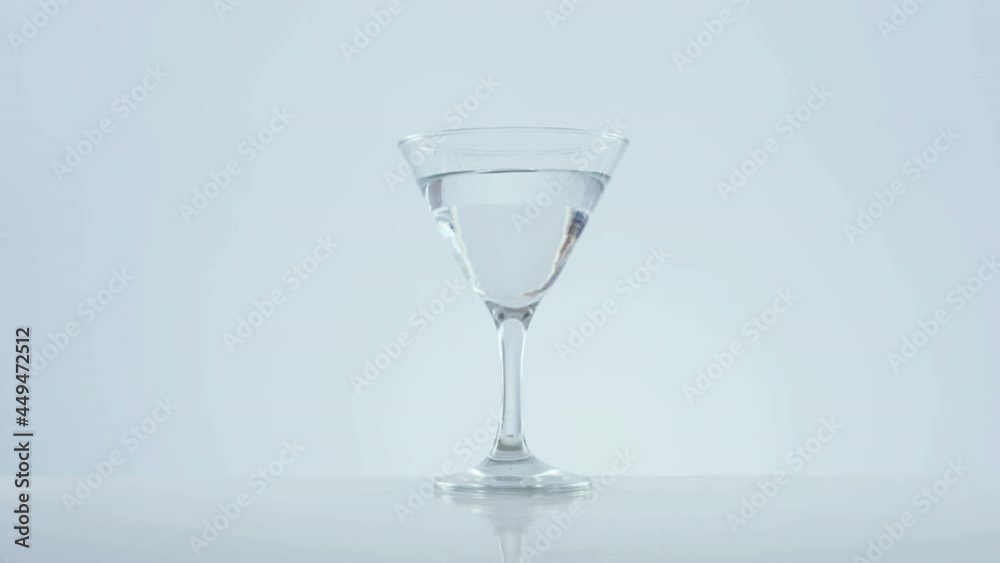 Golden confetti falling over olives falling into cocktail glass against grey background Golden confetti falling over olives falling into cocktail glass against grey background