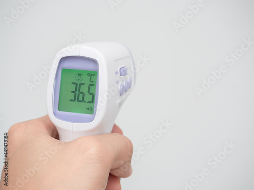 Hand holding infrared thermometer digital at white background