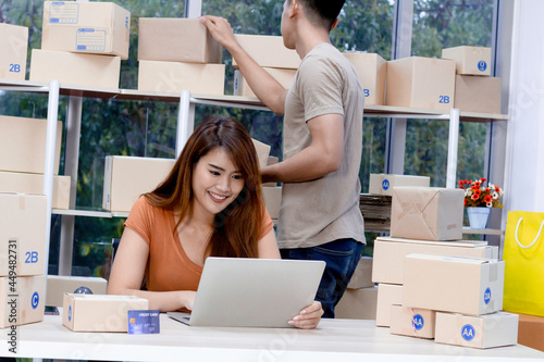 Business concept : Young couple starting small businesses SME owners entrepreneurs check online orders to prepare to pack the boxes, sell to customers, young business strat up. photo