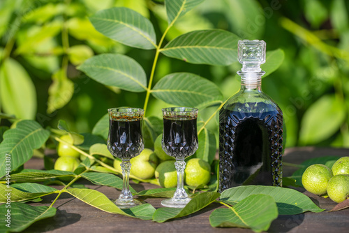 Liqueur from young green walnuts, remedy for stomach ache. Tincture of green walnuts in a glass bottle in the garden