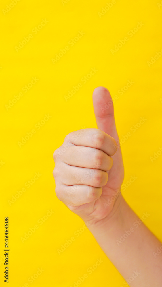Hand doing like with thumb on yellow background. Vertical