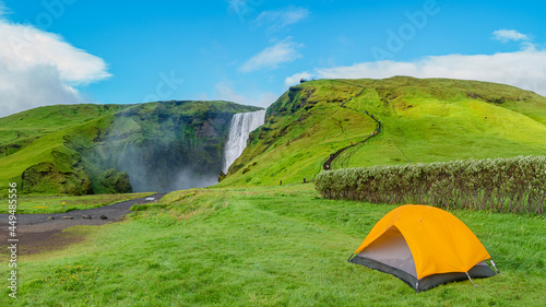 Canvas Print Panoramic view over camping site with orange tent, and tourists in front of famous Skogafoss waterfall, while hiking in Iceland, summer, scenic view