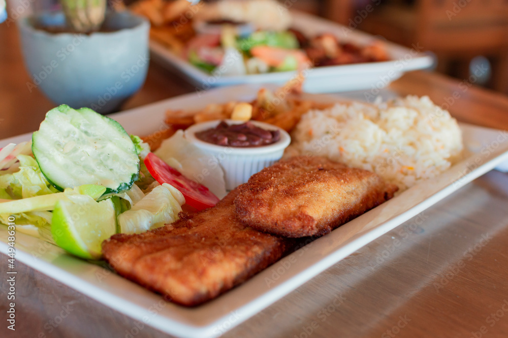 Breaded chicken with salad on wooden table with COPY SPACE, Close up of chicken fillet with salad, rice and beans Breaded chicken with salad on wooden table with COPY SPACE, Close up of chicken fillet with salad, rice and beans