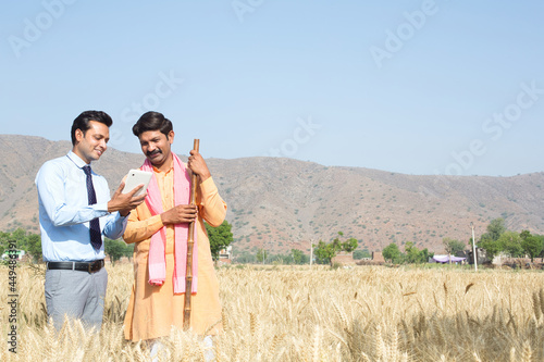 Farmer with agronomist examining wheat crop