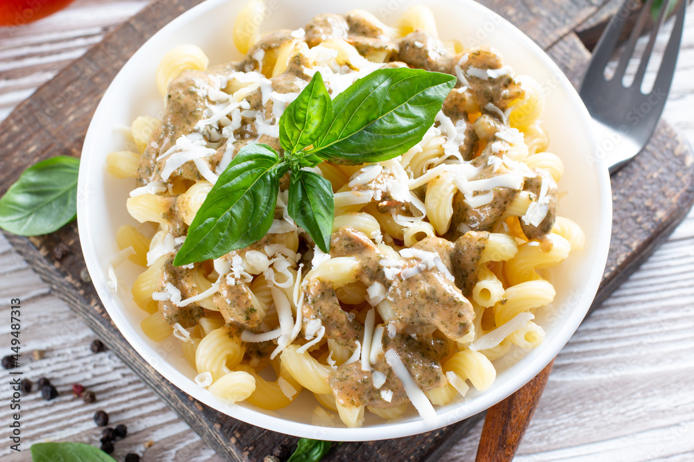 Pasta with spinach and cheese sauce on a light wooden background. Pasta with spinach and cheese sauce on a light wooden background.
